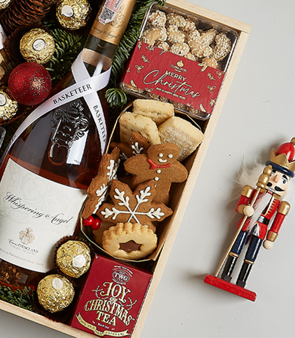 Christmas hamper with Château Montaud Rosé, mince pies, Ferrero Rocher chocolates, gingerbread cookies, festive greenery, and a nutcracker ornament.