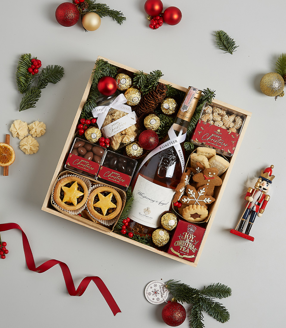 Christmas hamper with Château Montaud Rosé, mince pies, Ferrero Rocher chocolates, gingerbread cookies, festive greenery, and a nutcracker ornament.