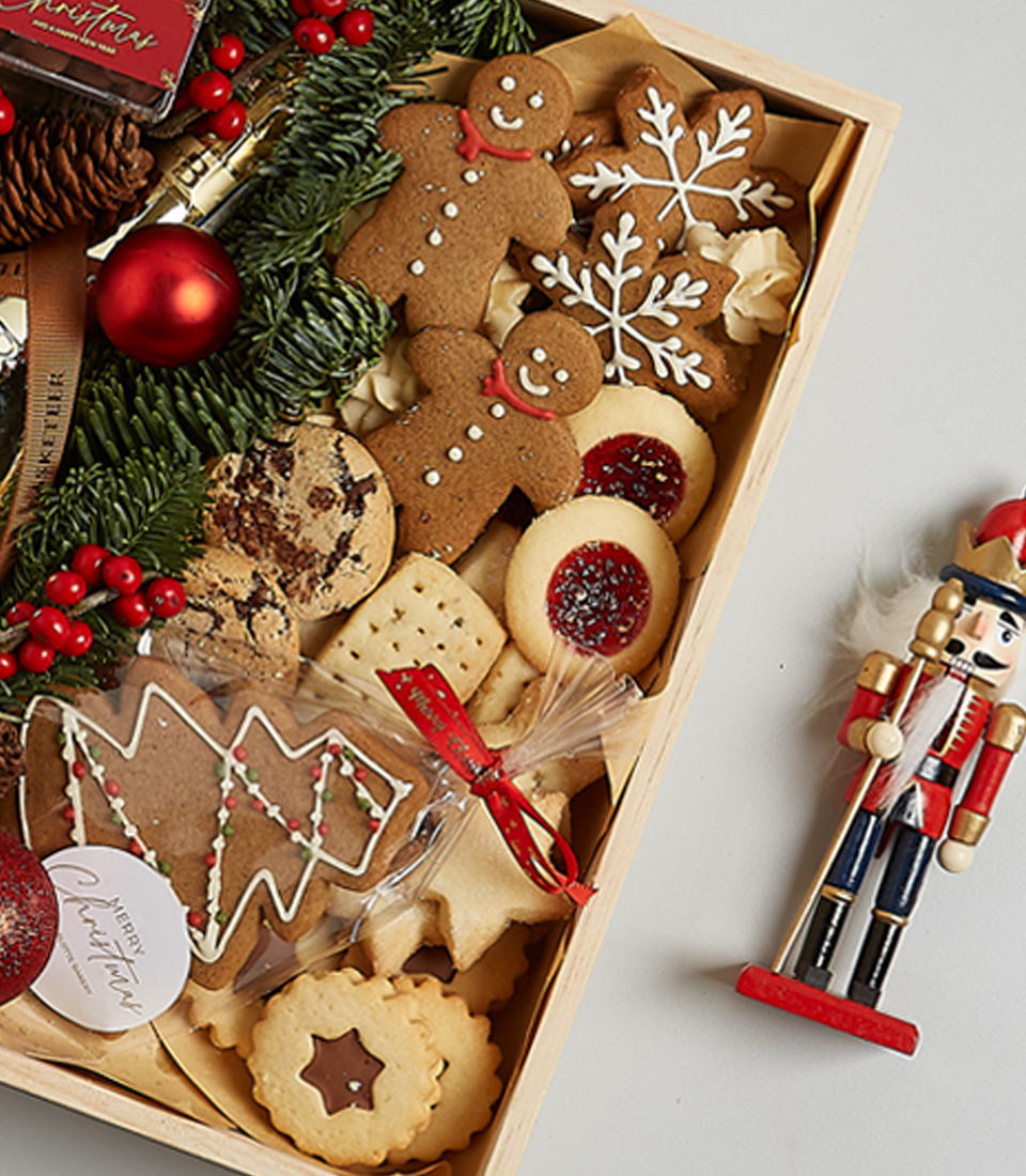 Festive gift box featuring Bottega Gold Prosecco, gingerbread cookies, chocolates, shortbread, holiday greenery, and nutcracker decoration.