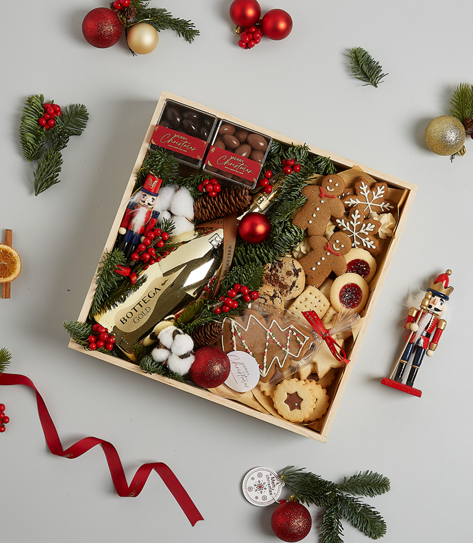 Festive gift box featuring Bottega Gold Prosecco, gingerbread cookies, chocolates, shortbread, holiday greenery, and nutcracker decoration.