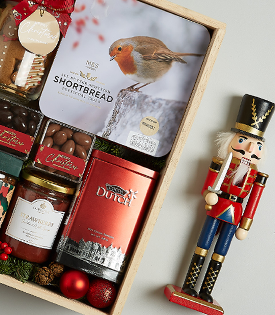 Christmas gift box featuring Moët & Chandon Champagne, shortbread biscuits, chocolates, preserves, and festive decorations.