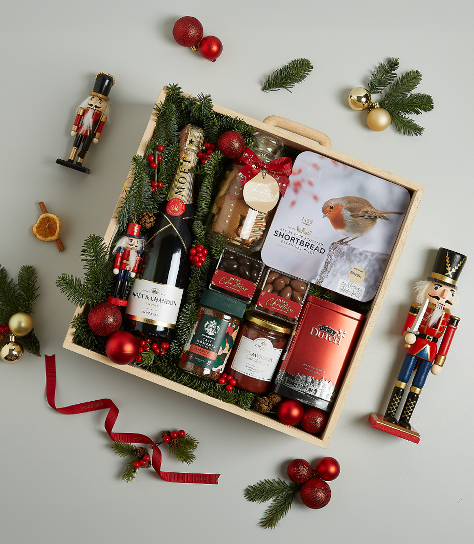 Christmas gift box featuring Moët & Chandon Champagne, shortbread biscuits, chocolates, preserves, and festive decorations.