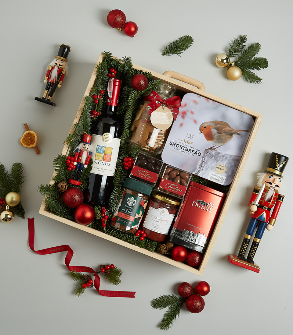 Christmas gift hamper featuring Signus wine, shortbread biscuits, chocolates, preserves, and festive decorations in a wooden box.