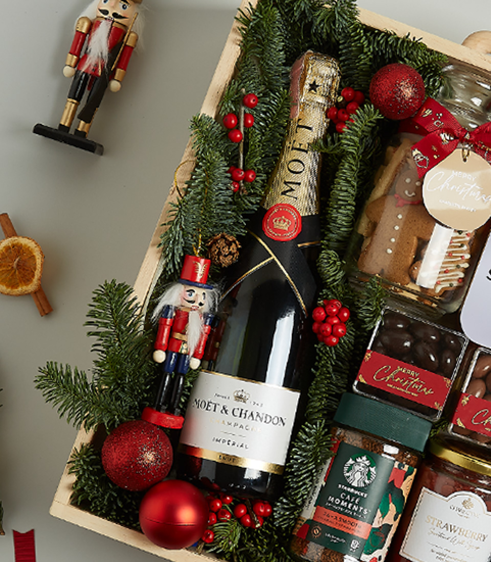 Christmas gift box featuring Moët & Chandon Champagne, shortbread biscuits, chocolates, preserves, and festive decorations.