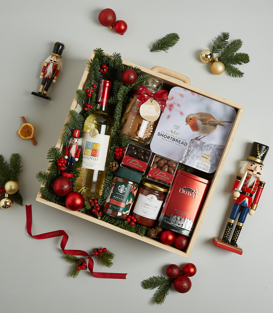 Festive Christmas hamper with Signus white wine, shortbread biscuits, chocolates, preserves, and holiday decorations in a wooden gift box.