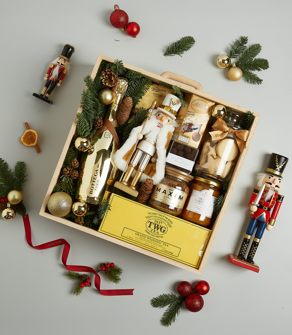 Christmas gift hamper with TWG tea, Bottega Gold prosecco, cookies, honey, gourmet spreads, and a nutcracker figurine in a festive wooden box.