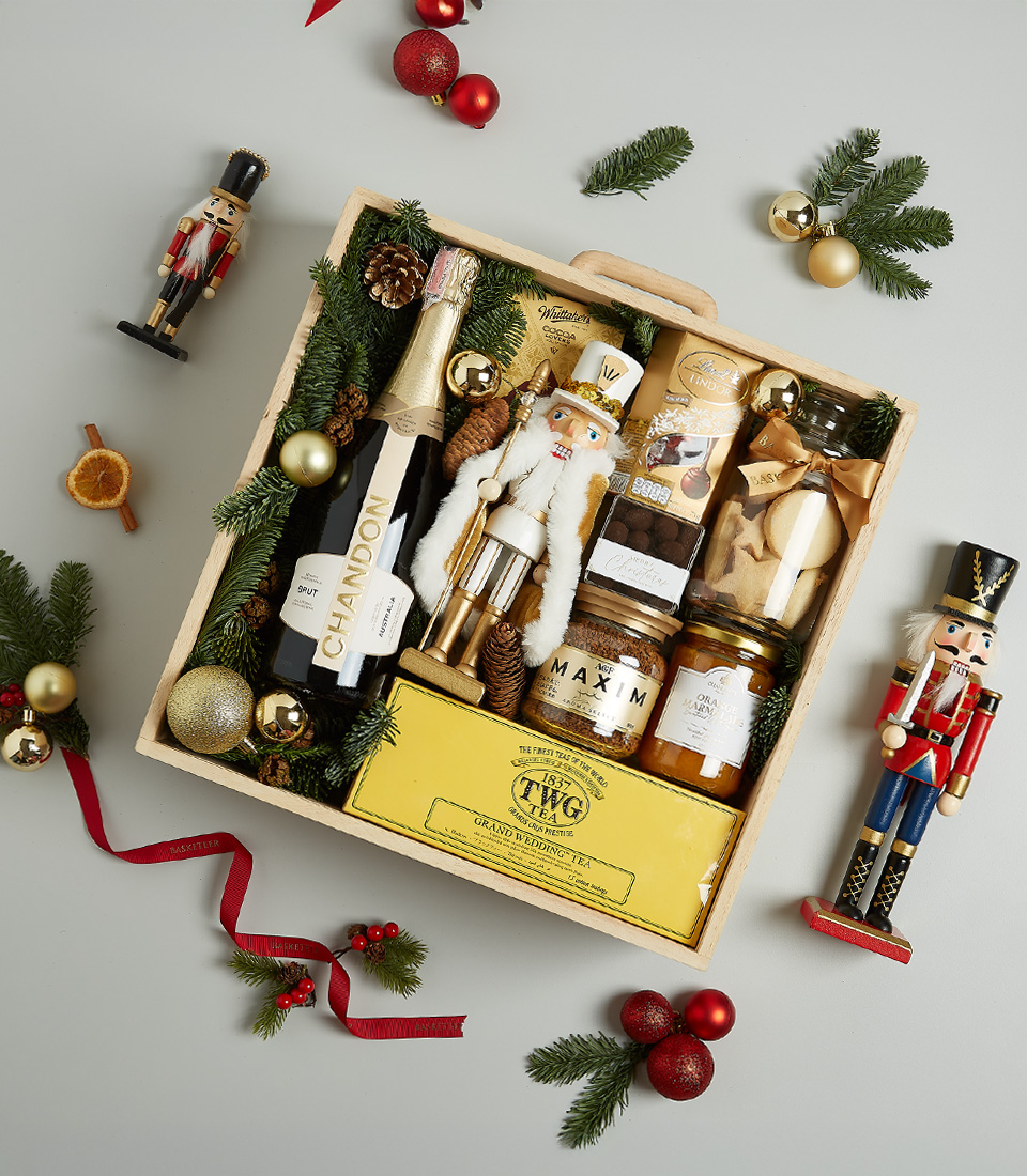 Christmas gift hamper with Chandon sparkling wine, TWG tea, gourmet honey, artisanal cookies, chocolates, and a Nutcracker decoration in holiday-themed packaging.