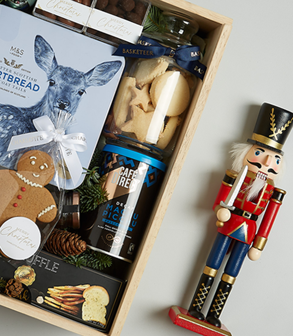 Premium Christmas gift hamper with Floralba sparkling wine, shortbread cookies, truffle crisps, Silver Moon tea, chocolate almonds, and festive gingerbread cookies, arranged in blue and silver holiday decor.