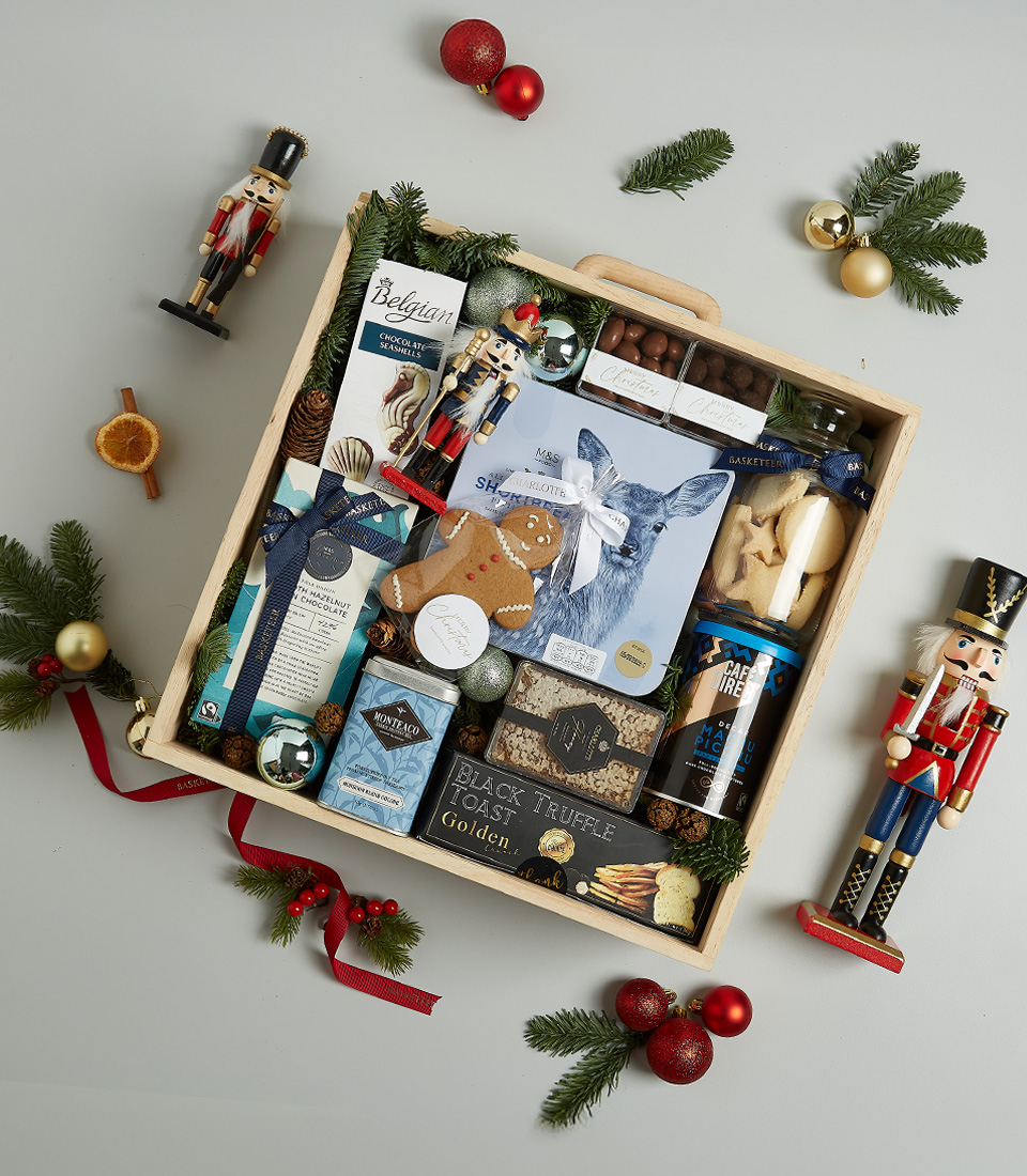Premium Christmas hamper with Belgian chocolates, shortbread cookies, truffle crisps, Silver Moon tea, chocolate nuts, and festive gingerbread cookies, decorated with nutcrackers and holiday ornaments.