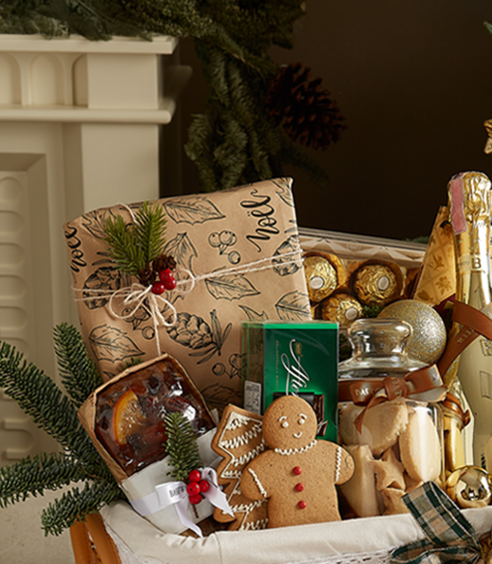 Luxurious Christmas gift basket featuring Bottega Gold Prosecco, gingerbread cookies, fruitcake, mince pies, and chocolates with festive decorations.