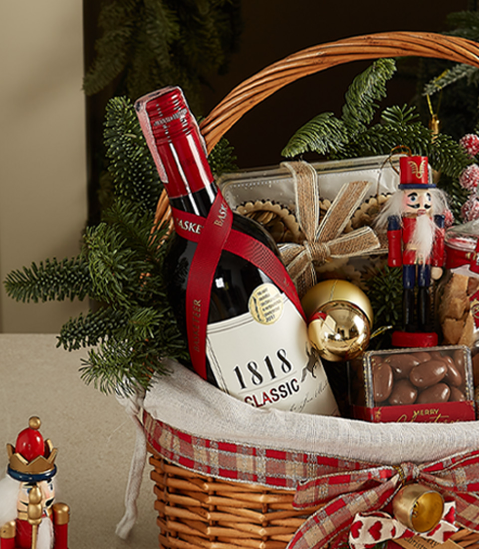 Holiday wicker hamper with 1818 Classic red wine, cookies, chocolates, nutcracker figurine, and festive decorations.