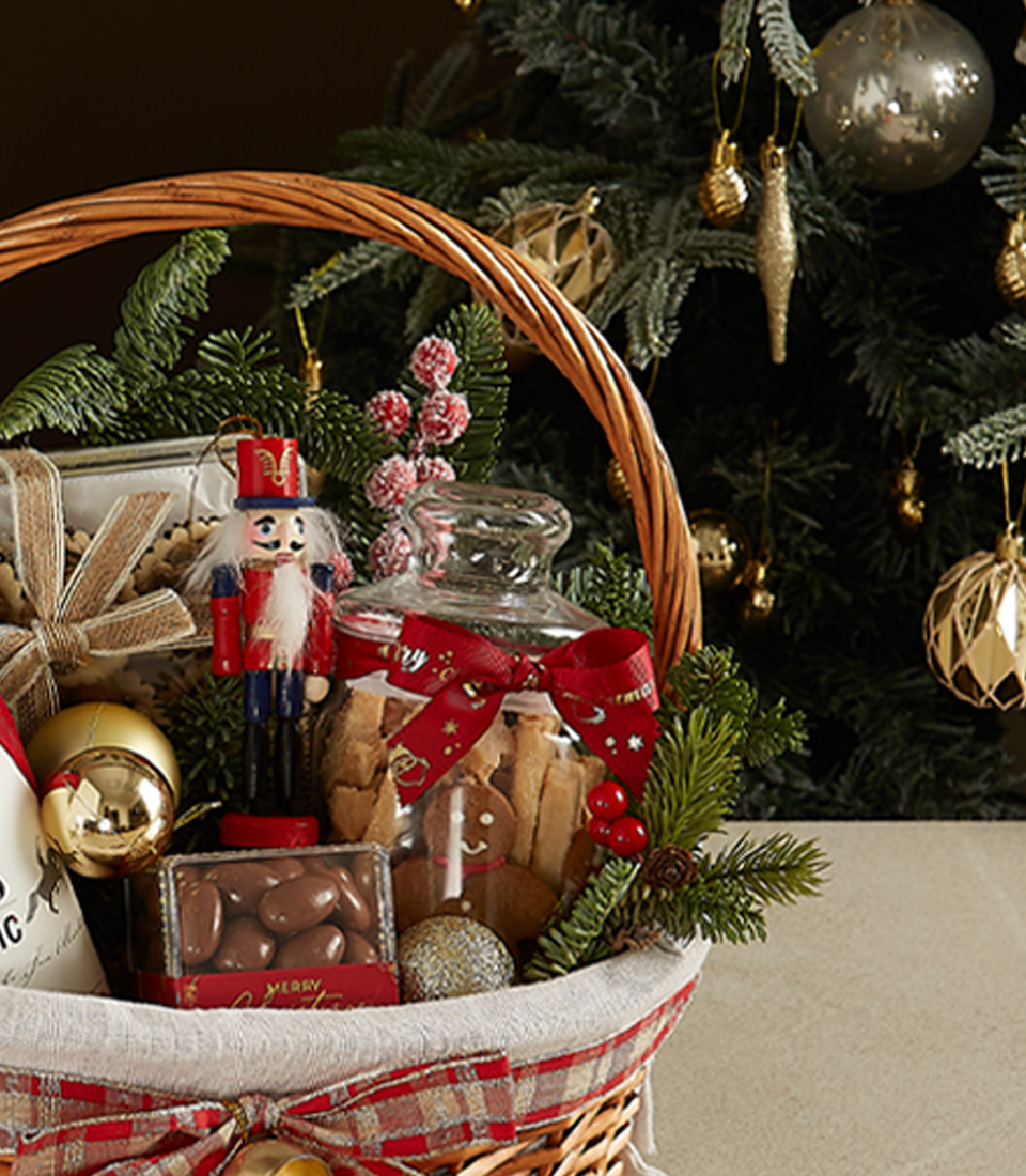 Holiday wicker hamper with 1818 Classic red wine, cookies, chocolates, nutcracker figurine, and festive decorations.