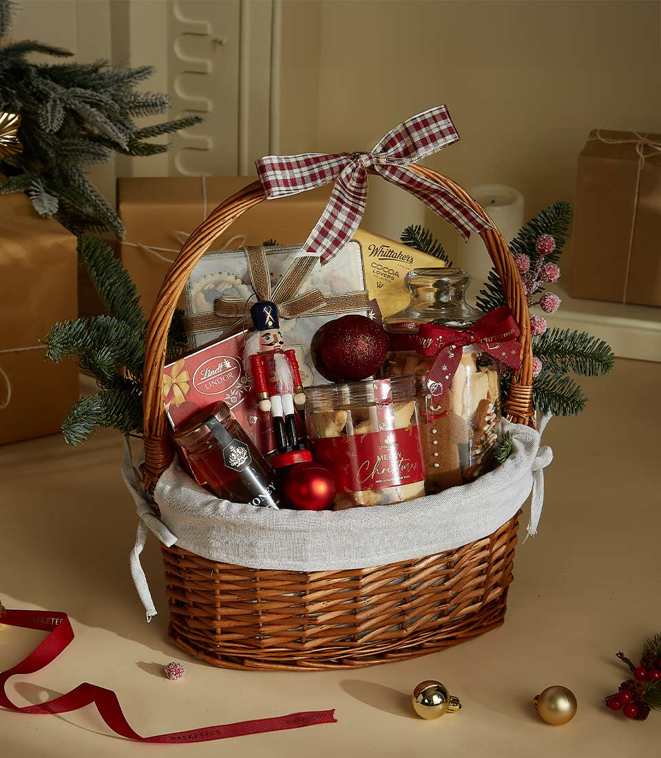 Christmas gift basket with festive cookies, chocolates, a nutcracker figurine, and holiday decorations arranged in a wicker basket with ribbon accents.