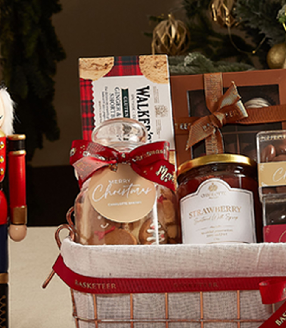 Classic holiday gift basket with cookies, jam, tea, and festive decorations, ideal for seasonal gifting.