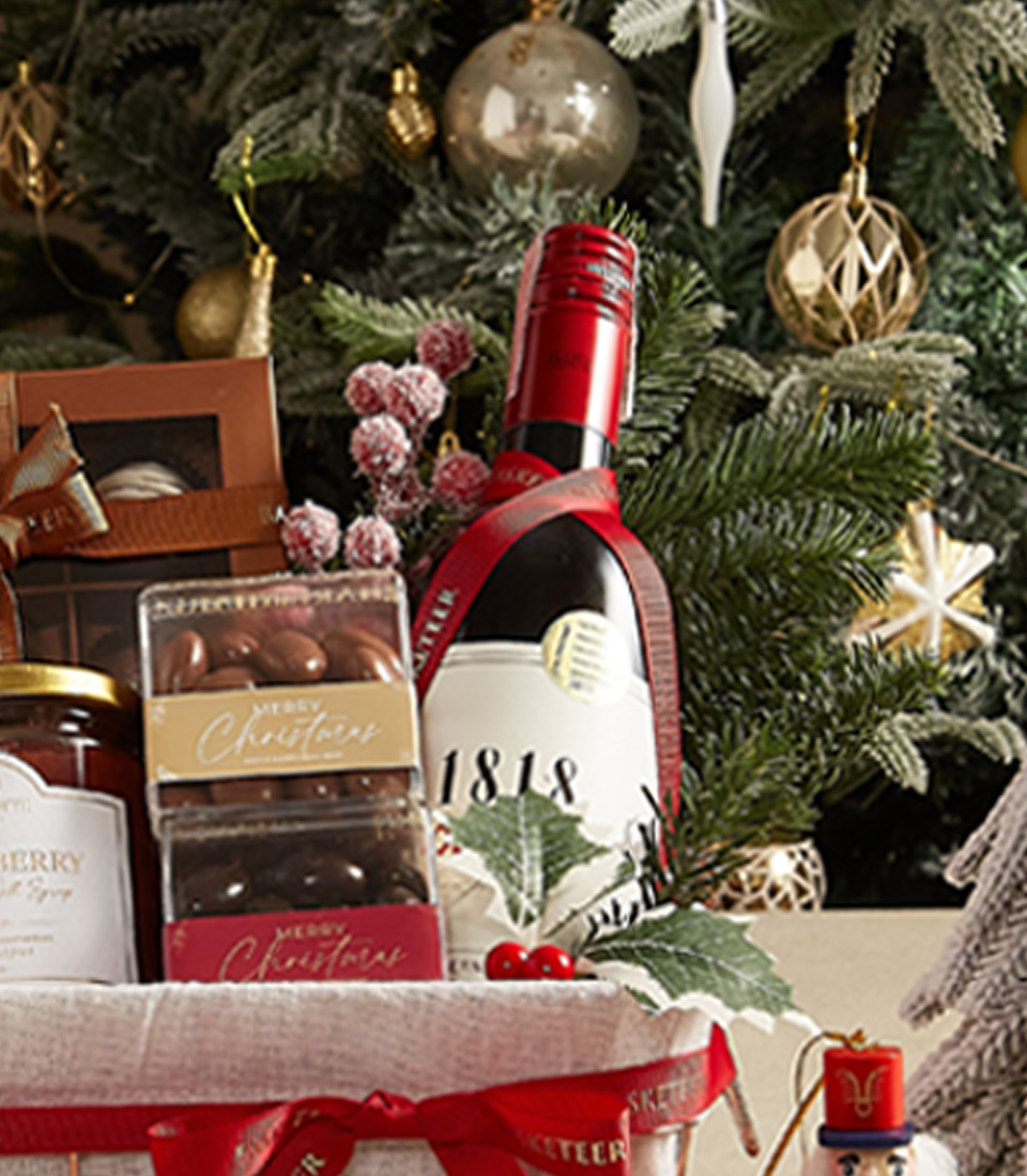 Classic holiday gift basket with cookies, jam, tea, and festive decorations, ideal for seasonal gifting.