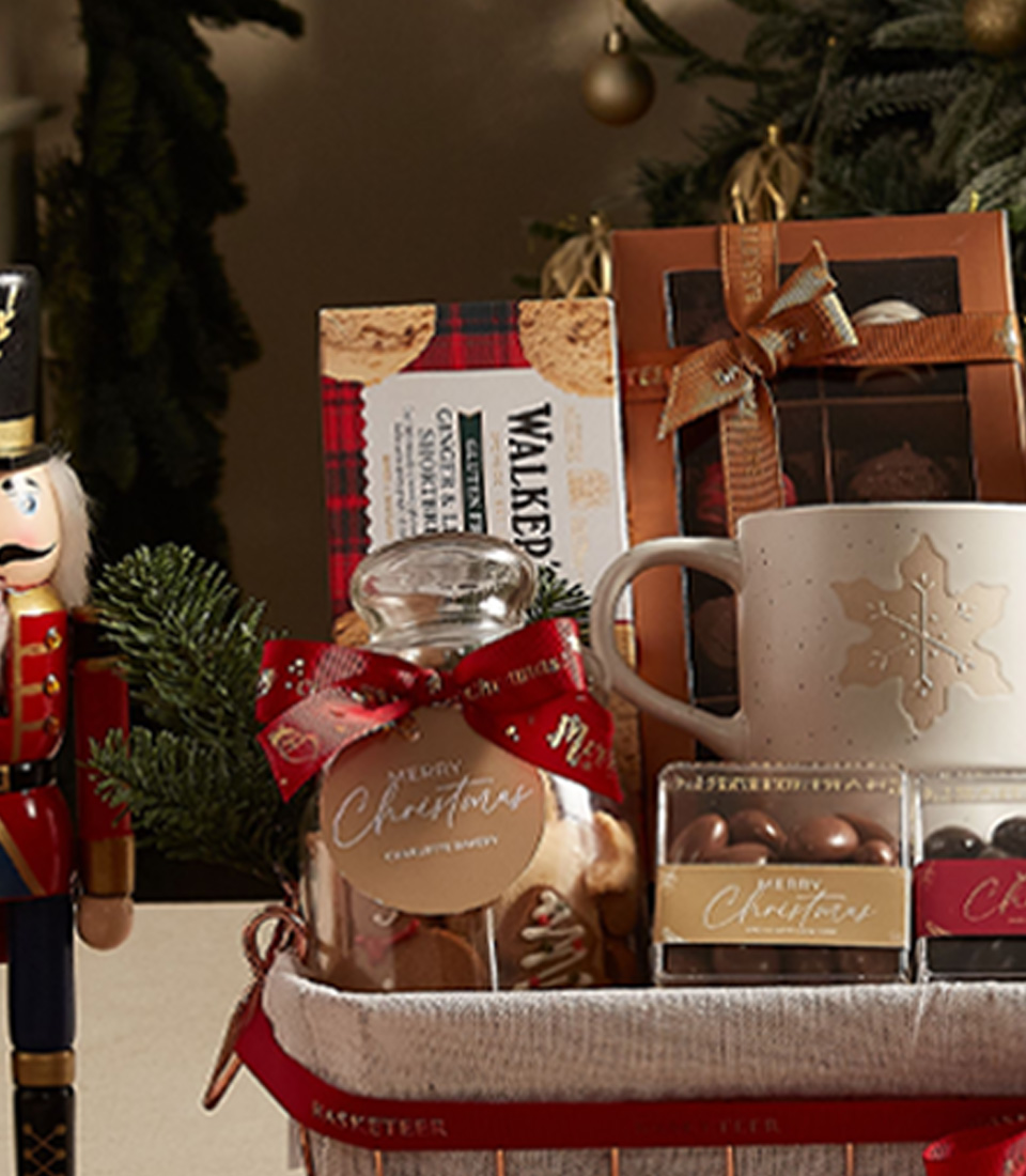 Festive gift basket with a holiday mug, cookies, chocolates, and seasonal decorations, ideal for gifting.