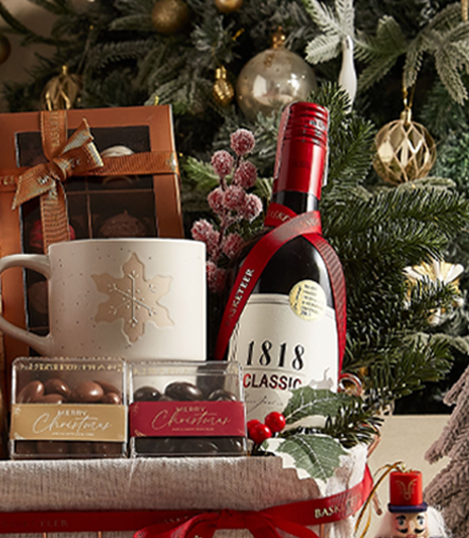 Festive gift basket with a holiday mug, cookies, chocolates, and seasonal decorations, ideal for gifting.