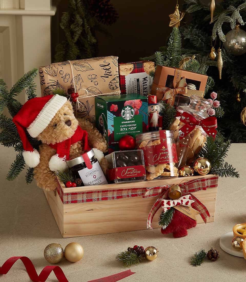Wooden gift crate with a Santa teddy bear, coffee, chocolates, cookies, and festive holiday decorations.
