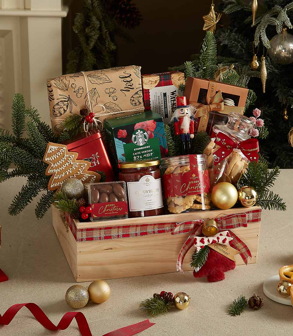 Wooden gift crate with Starbucks coffee, chocolates, cookies, gingerbread ornament, and festive holiday decorations.