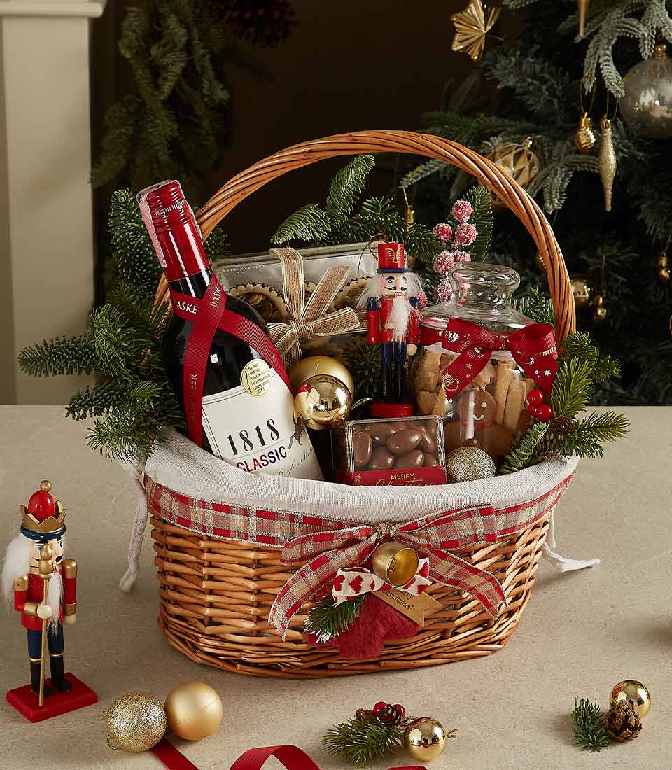 Holiday wicker hamper with 1818 Classic red wine, cookies, chocolates, nutcracker figurine, and festive decorations.