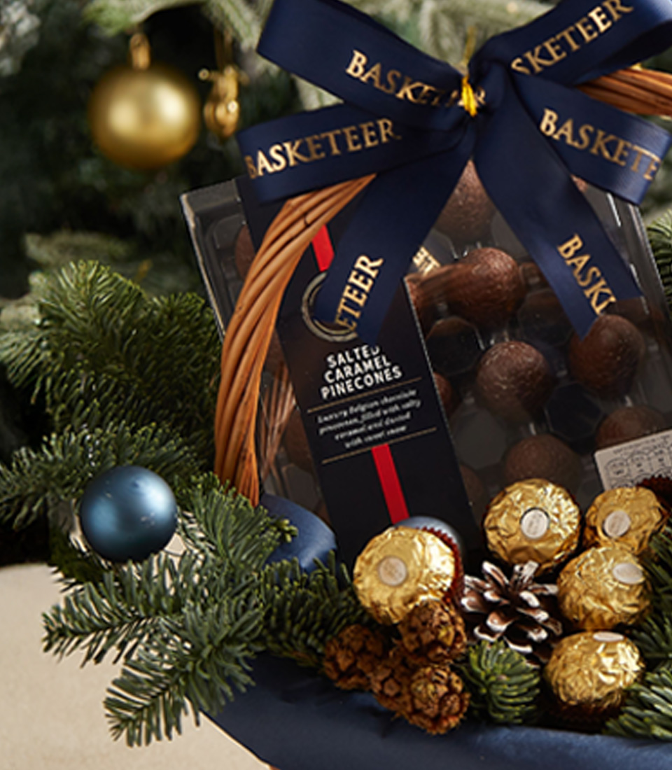 Holiday gift basket with blue ribbon, festive greenery, and premium treats for a perfect seasonal gift.