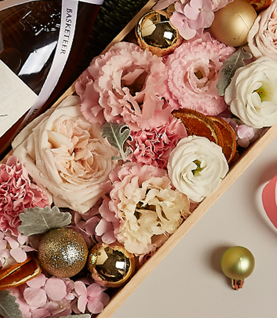 Luxury floral gift box with pastel blooms, golden accents, and festive decorations for the holiday season.