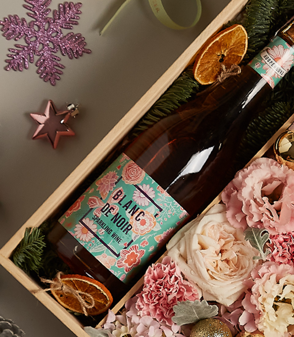 Floral gift box with pastel roses, golden accents, and festive decorations, ideal for special occasions.