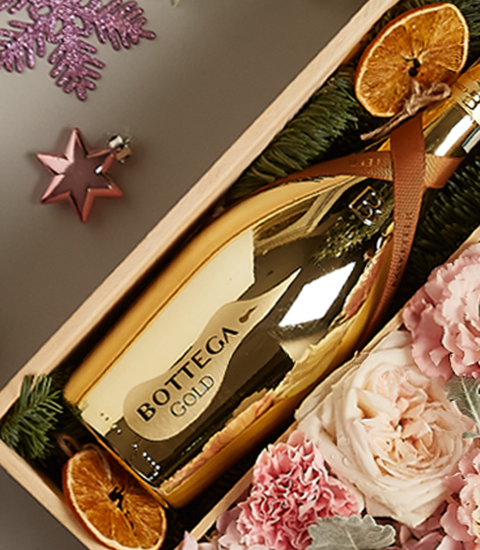 Blush and gold-themed gift hamper featuring Bottega Gold Prosecco, pastel floral arrangements, and festive decorations.