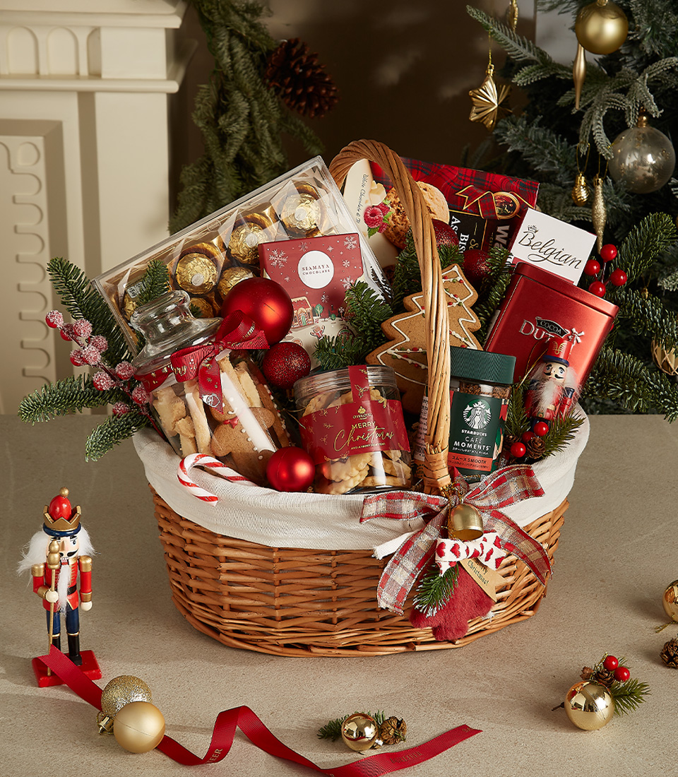 Wicker gift basket filled with Belgian chocolates, cookies, Starbucks coffee, gingerbread, and festive holiday decorations.