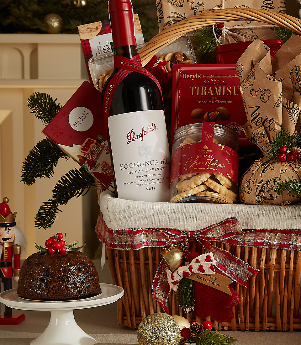 Luxurious holiday wicker hamper with premium wine, plum pudding, fruit mince pies, tiramisu biscuits, cookies, and festive ornaments.