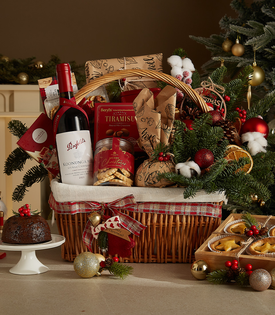 Luxurious holiday wicker hamper with premium wine, plum pudding, fruit mince pies, tiramisu biscuits, cookies, and festive ornaments.
