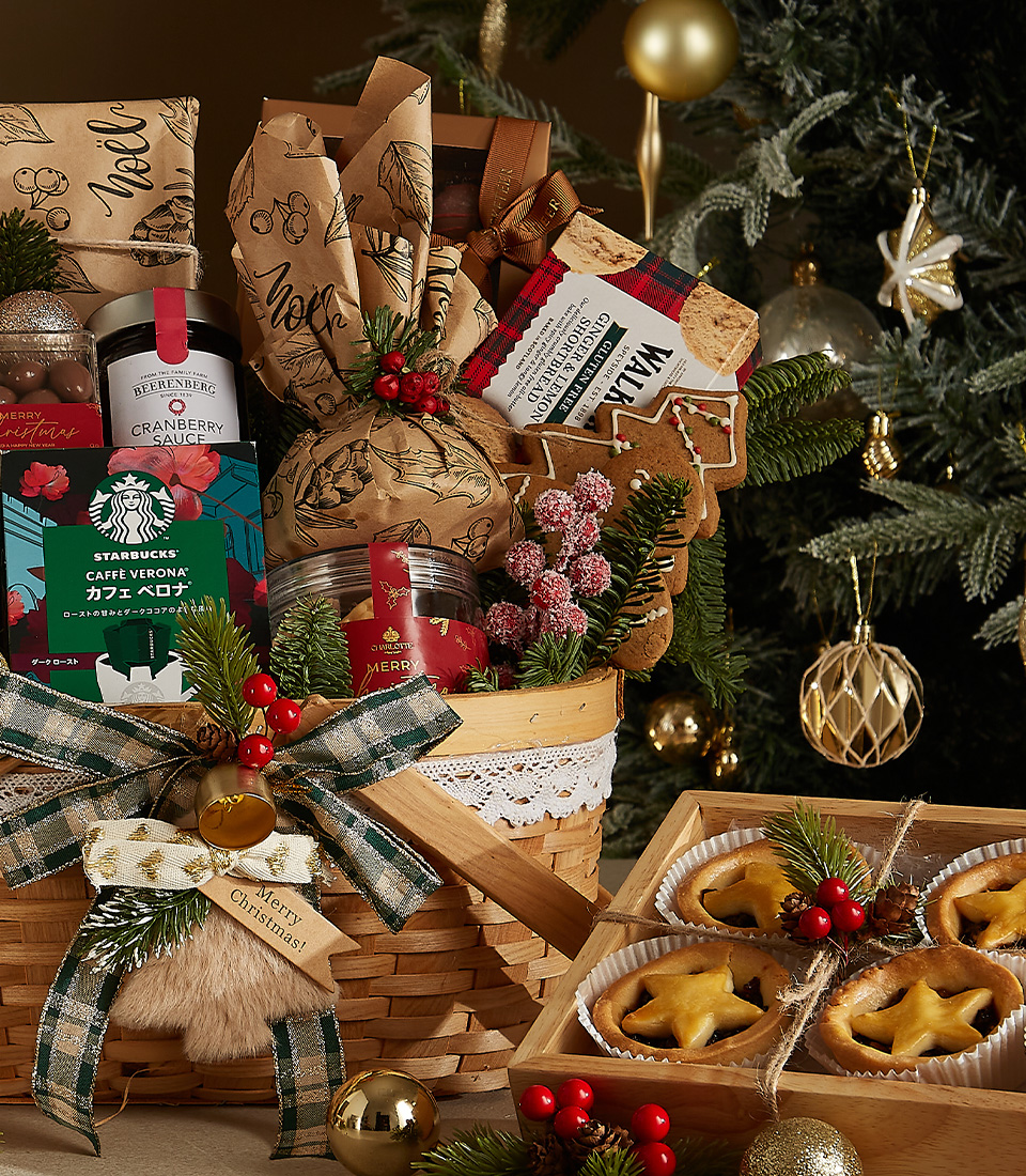 Festive wicker hamper filled with champagne, gourmet coffee, fruit pies, plum pudding, artisan cookies, and holiday decorations.