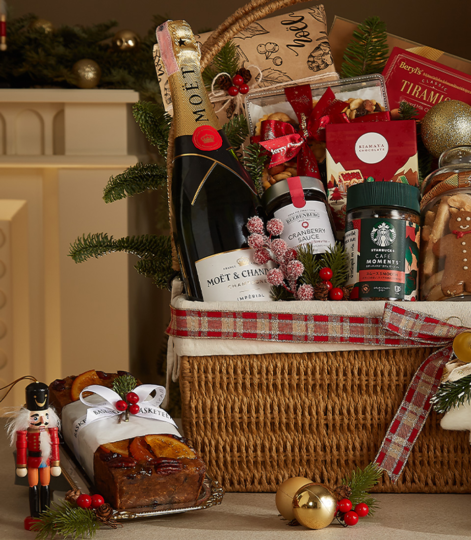 Luxury holiday gift hamper featuring Moët & Chandon champagne, Starbucks coffee, gingerbread cookies, mince pies, fruitcake, and festive decor.