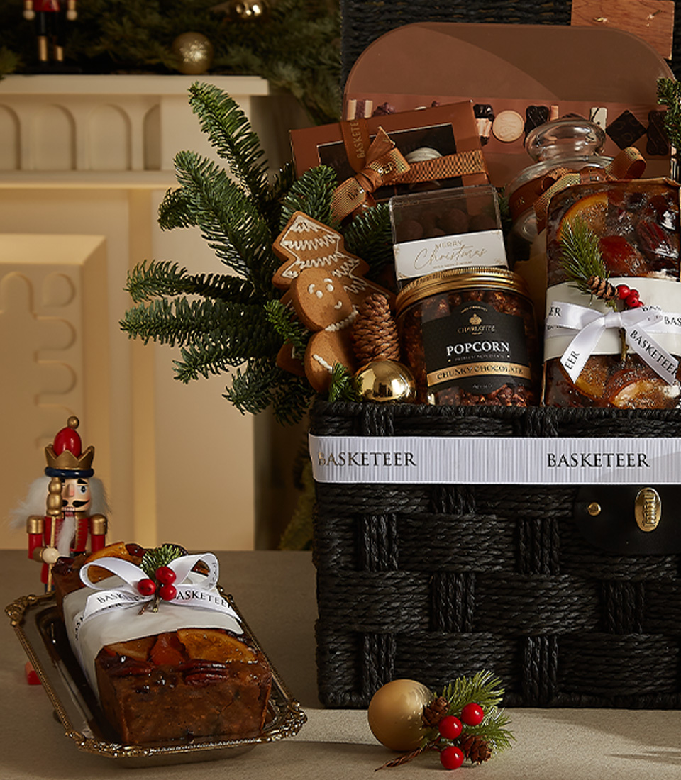 Sophisticated black wicker Christmas hamper with Bailey's, popcorn, mince pies, chocolates, and seasonal decorations.