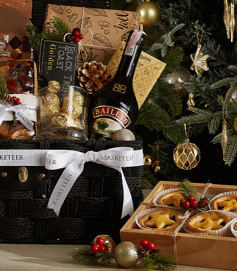 Sophisticated black wicker Christmas hamper with Bailey's, popcorn, mince pies, chocolates, and seasonal decorations.