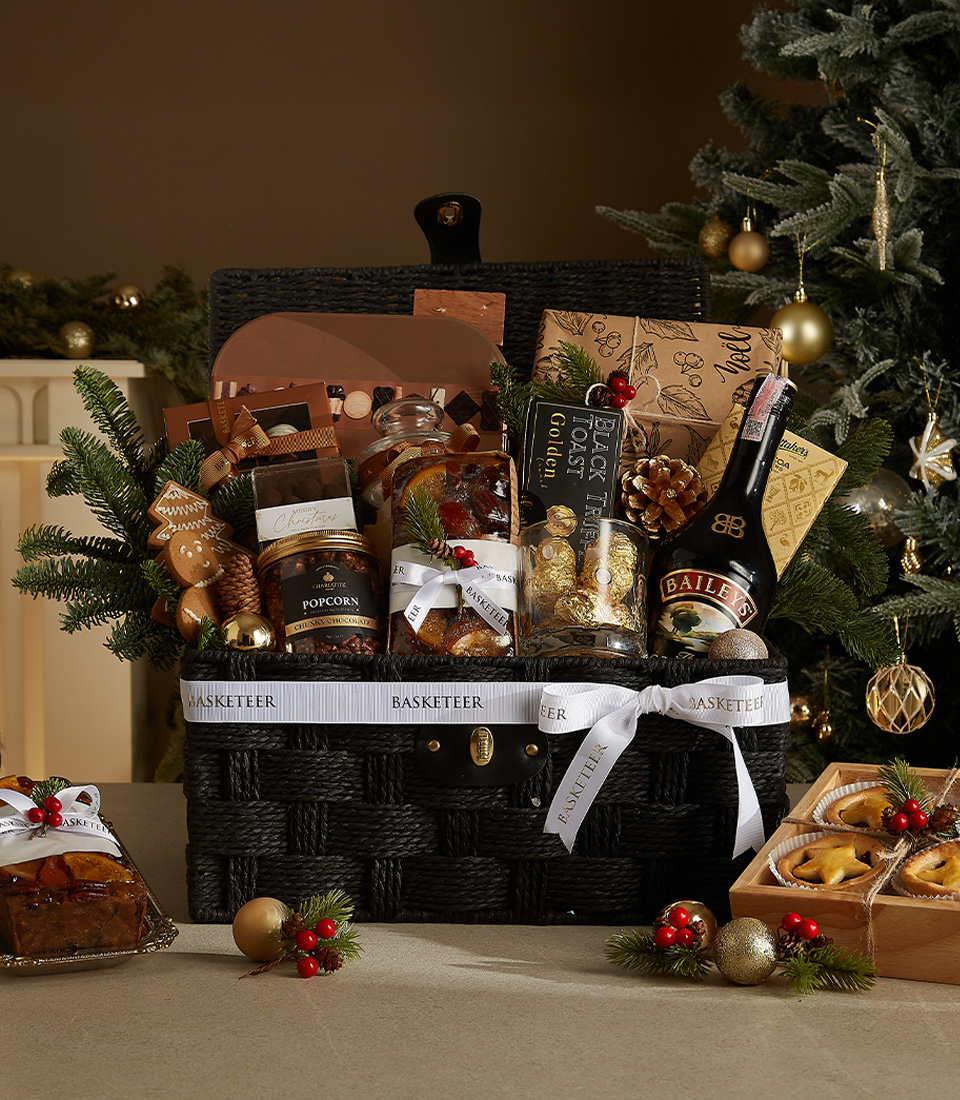 Sophisticated black wicker Christmas hamper with Bailey's, popcorn, mince pies, chocolates, and seasonal decorations.
