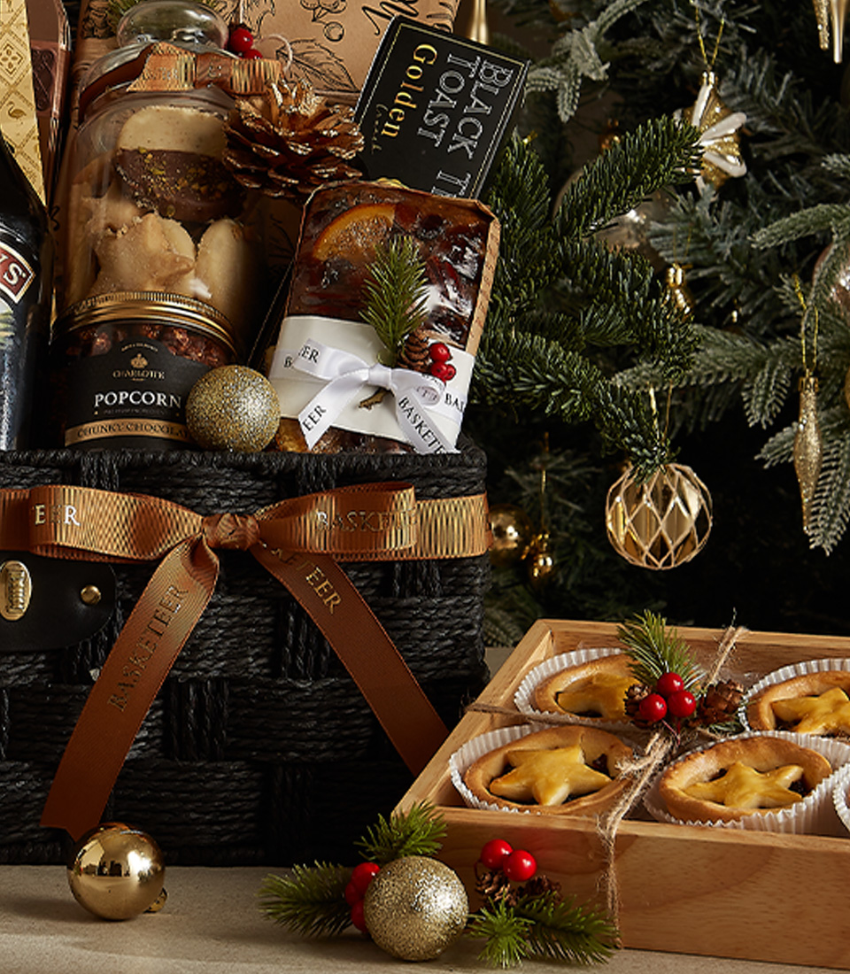 Elegant black Christmas hamper with Bailey's Irish Cream, fruit pudding, mince pies, gourmet treats, and festive decorations.