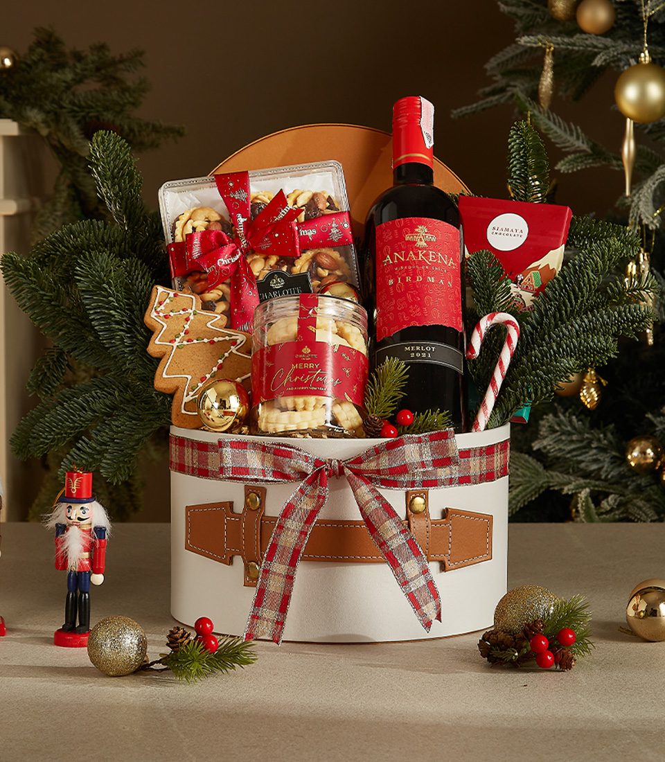 White Christmas gift box with leather accents and plaid ribbon, containing Anakena red wine, butter cookies, gingerbread, candy canes, and festive chocolates.