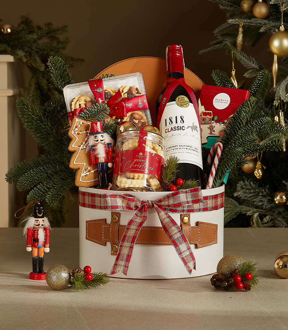 White gift box with leather accents and plaid ribbon featuring 1818 Classic Red Wine, butter cookies, gingerbread, and holiday chocolates.