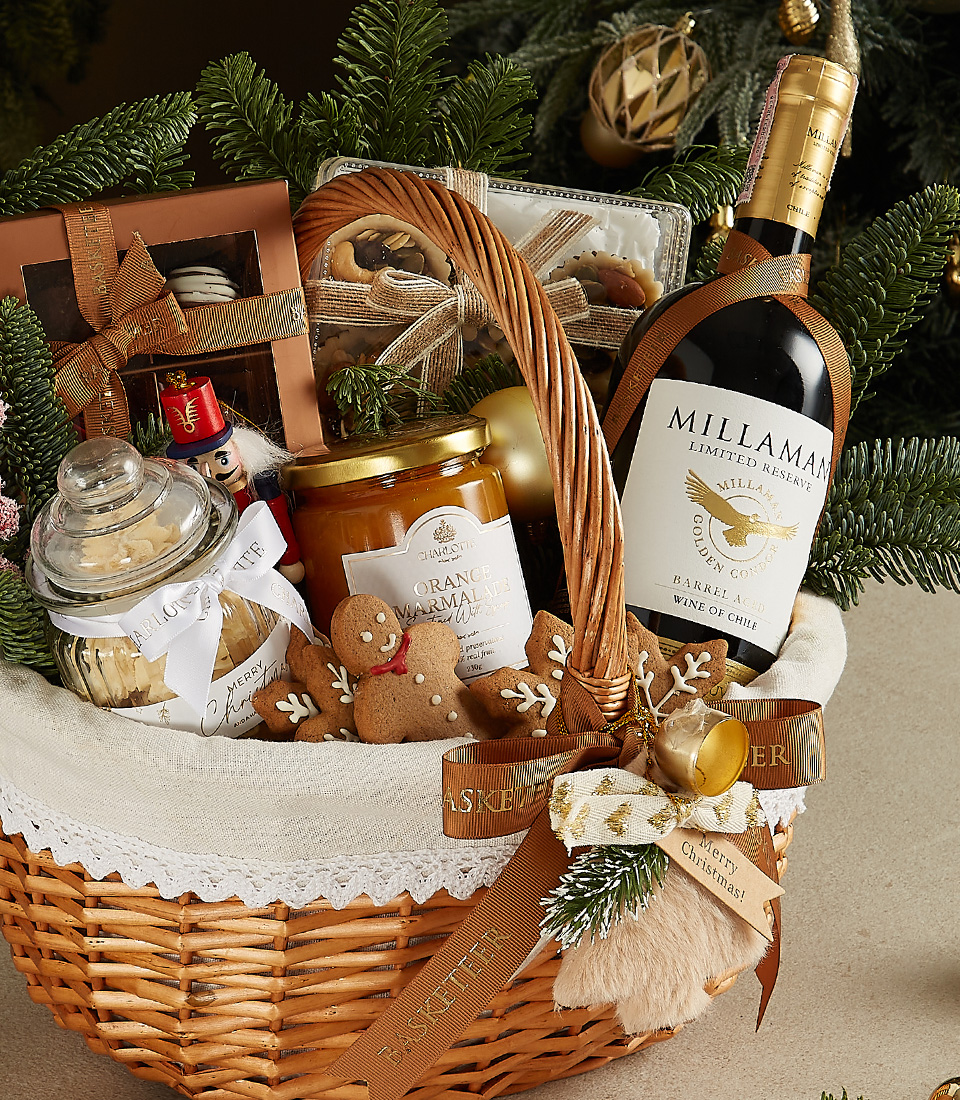 Elegant wicker basket with Millaman wine, gingerbread cookies, chocolates, honey jar, and festive decorations.
