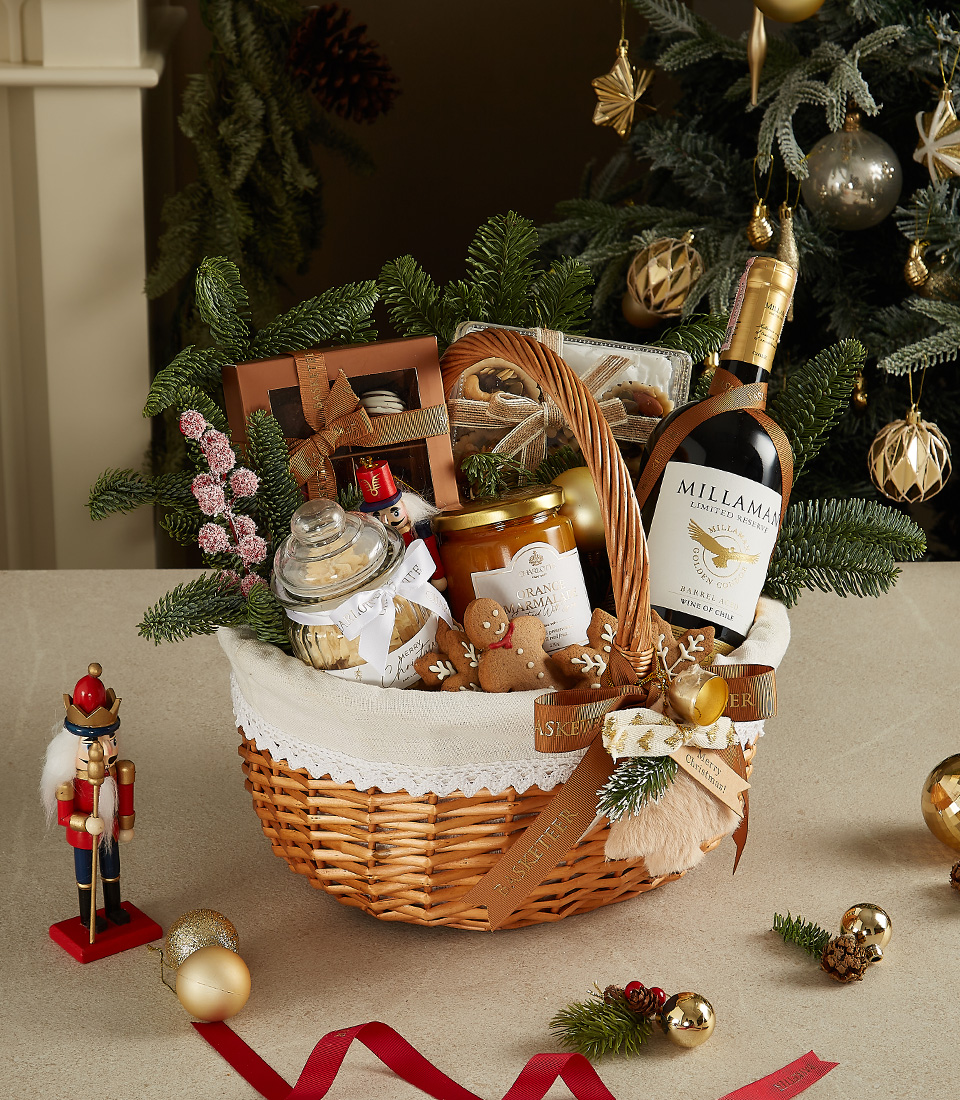 Elegant wicker basket with Millaman wine, gingerbread cookies, chocolates, honey jar, and festive decorations.