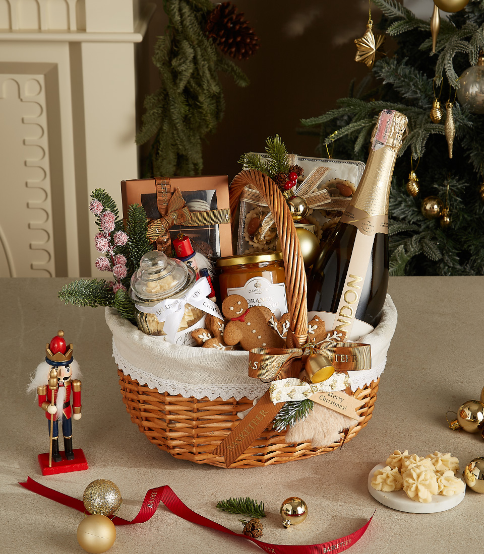 Wicker basket with Chandon champagne, gingerbread cookies, honey jar, shortbread cookies, and festive decorations.