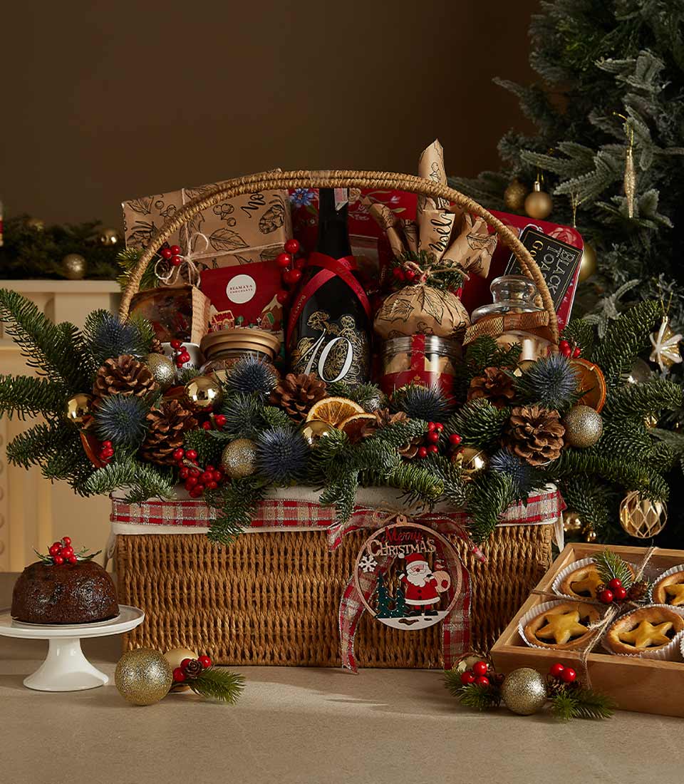 Luxurious Christmas hamper with red wine, Christmas pudding, mince pies, festive cookies, chocolates, and seasonal decorations.