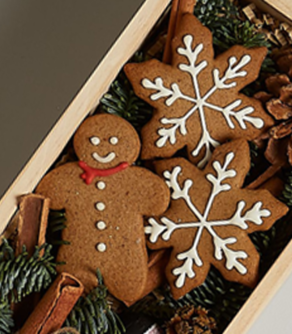 Holiday-themed gift box with Freixenet Prosecco, gingerbread cookies, and festive decorations in a wooden box.