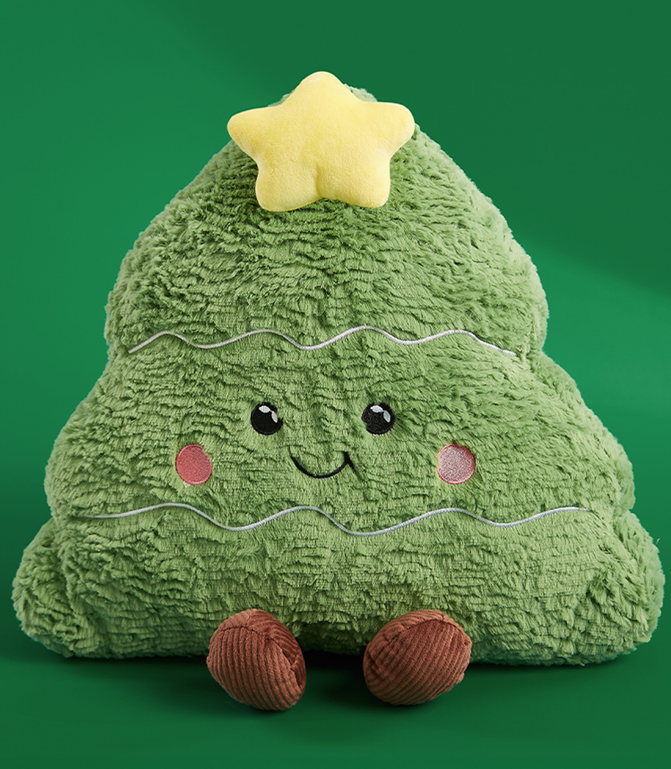 Plush Christmas tree toy with a cute smiling face, a yellow star on top, and brown feet on a green background.