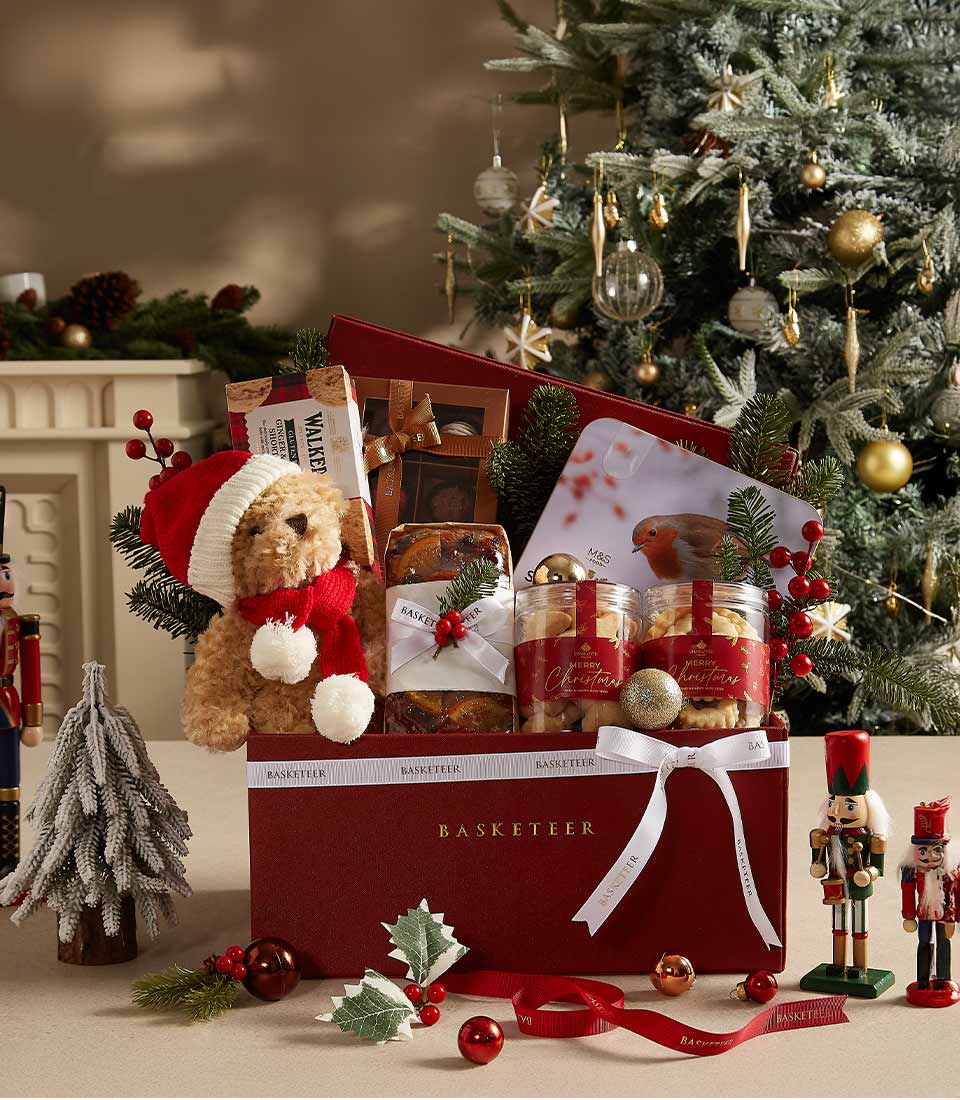 Holiday gift box with teddy bear, cookies, fruitcake, and festive treats, beautifully packaged for Christmas gifting.