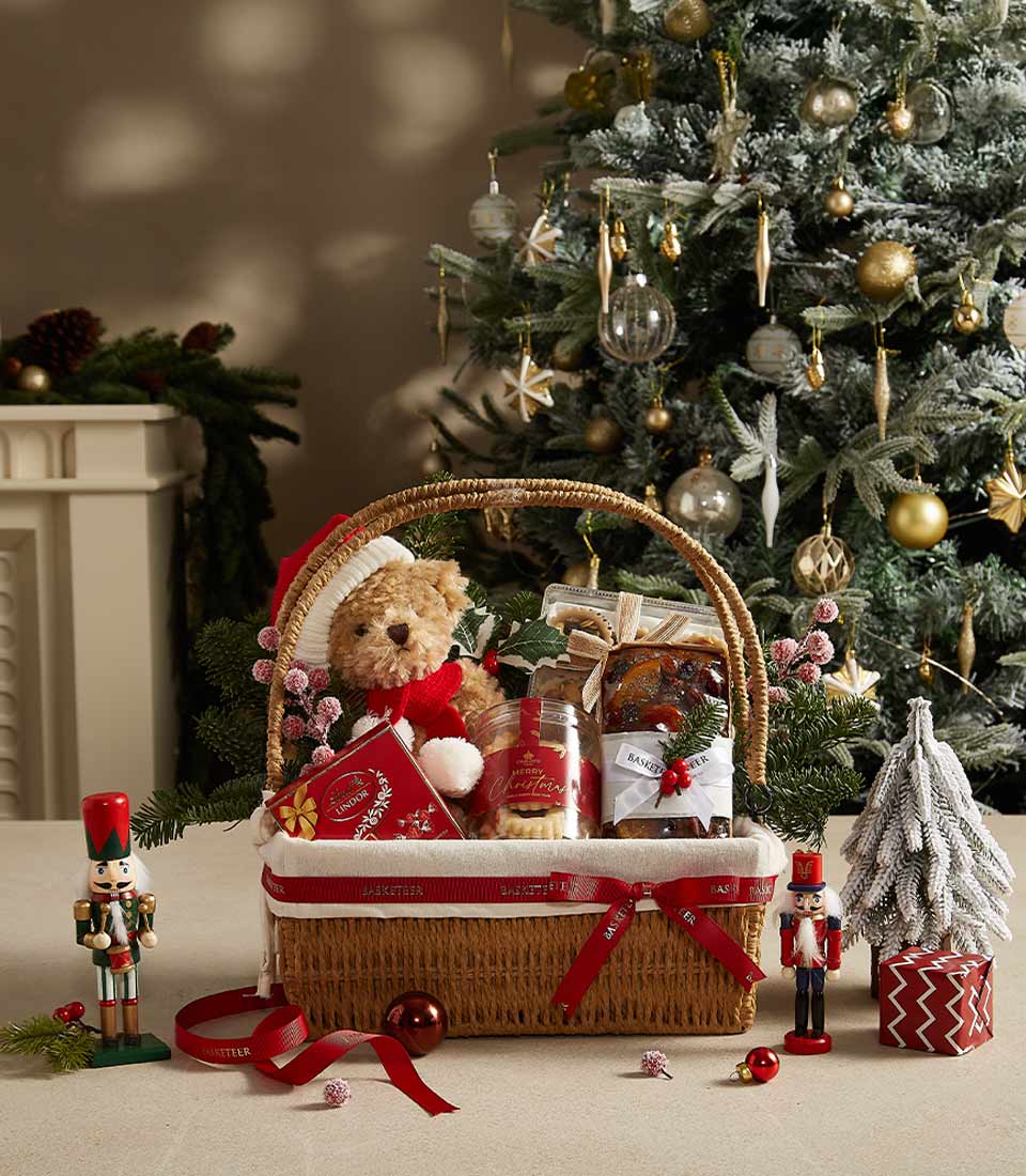Holiday gift basket with teddy bear, fruitcake, cookies, and festive treats, perfect for Christmas celebrations.
