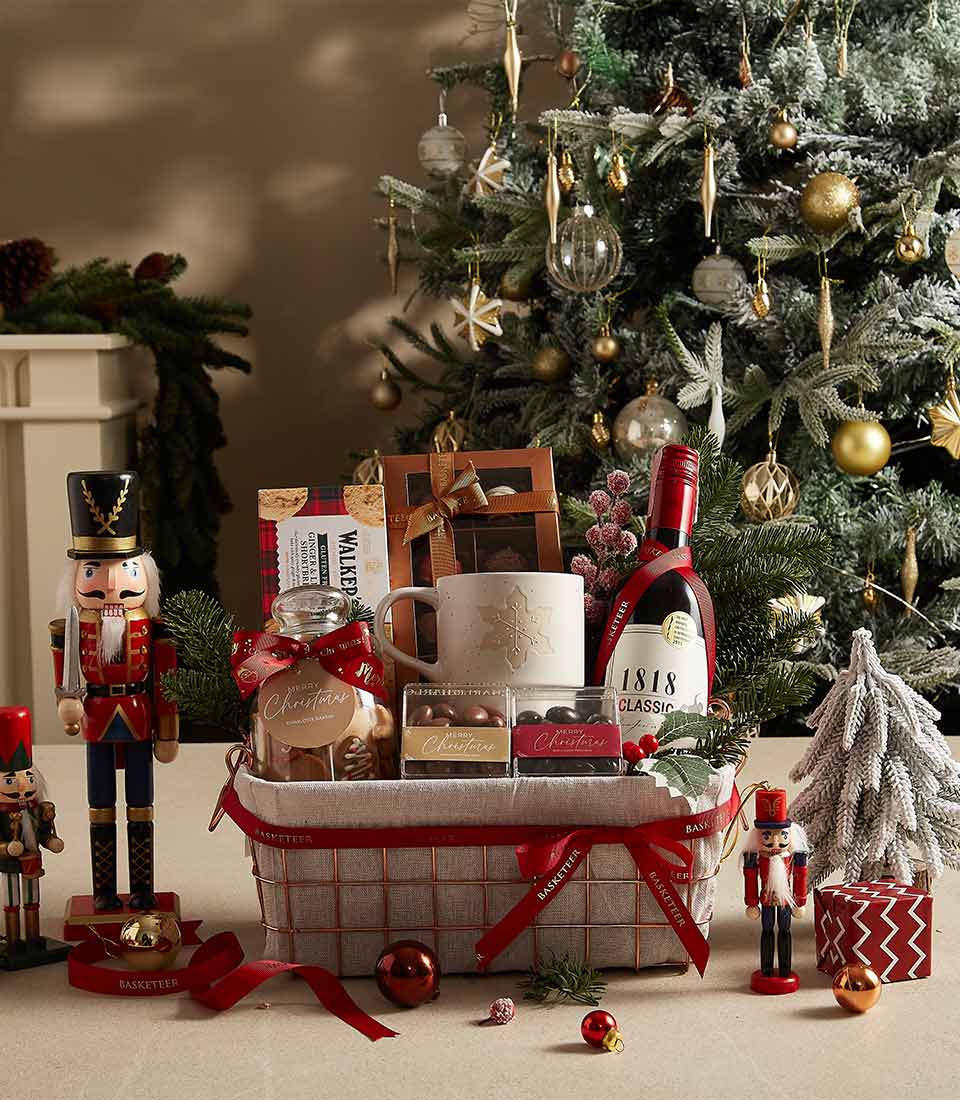 Festive gift basket with a holiday mug, cookies, chocolates, and seasonal decorations, ideal for gifting.