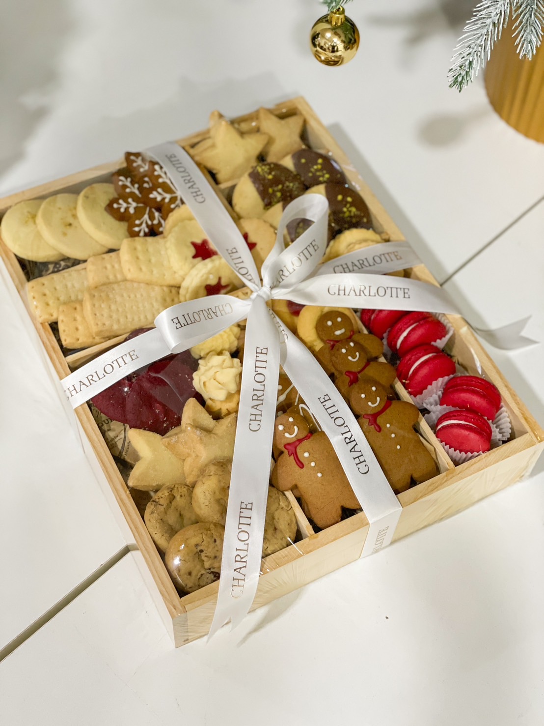 A charming wooden box brimming with Charlotte’s artisan biscuits, gingerbread men, and macarons, elegantly gift-wrapped for the holidays.