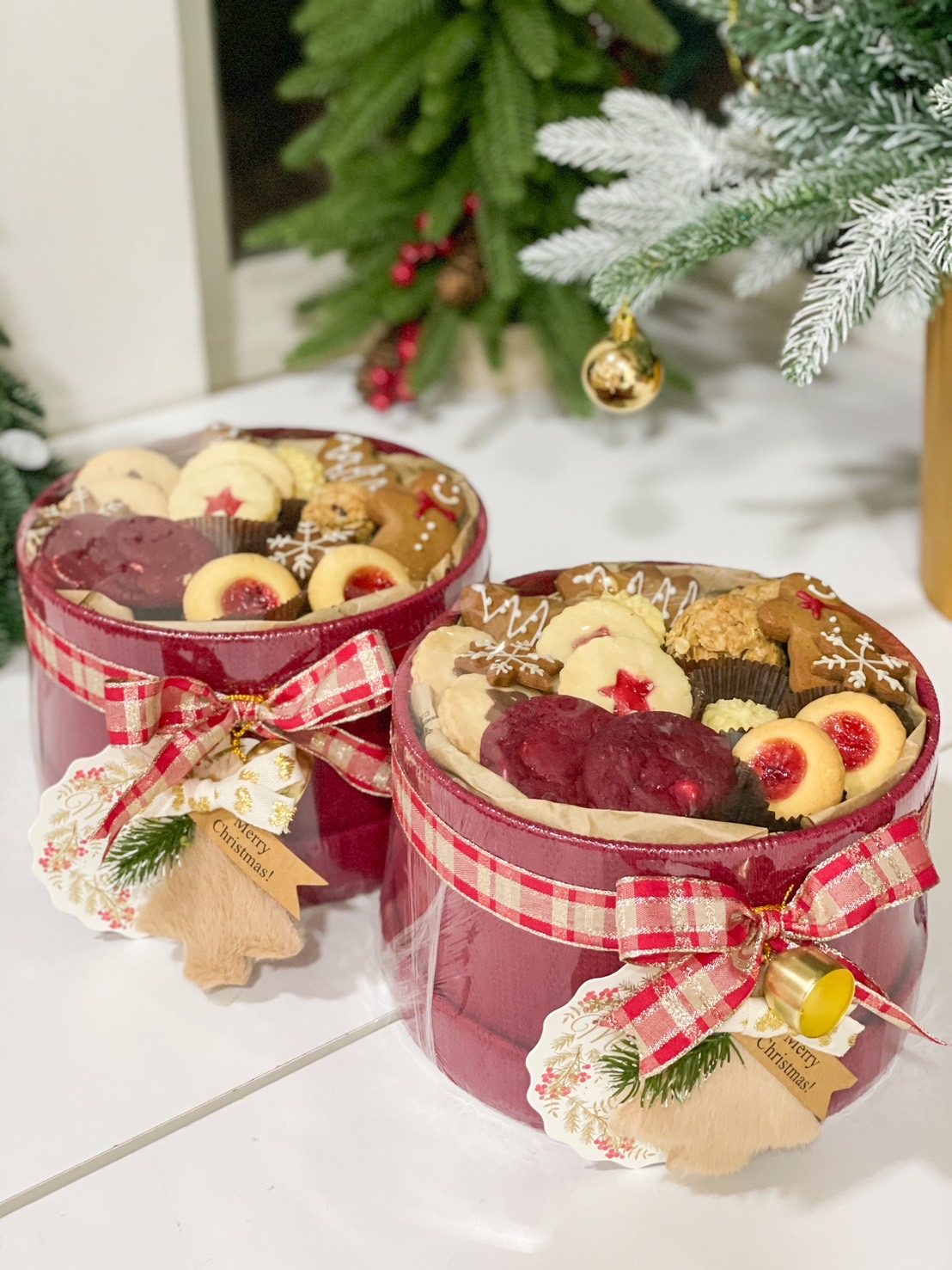Christmas-themed cookie jar filled with assorted holiday cookies, wrapped with a red ribbon and a festive tag.